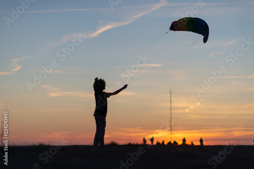 Kid playing with stunt kite at sunset
