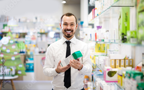 Positive male customer browsing rows of drugs