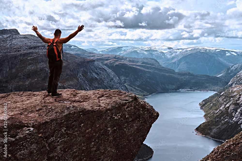 Obraz premium Turystyczny człowiek stojący w Trolltunga i ma piękny widok na norweski fiord.