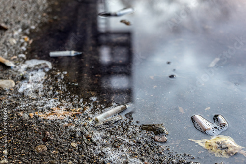 cigarette butts and leaves in autumn puddle. selective focus