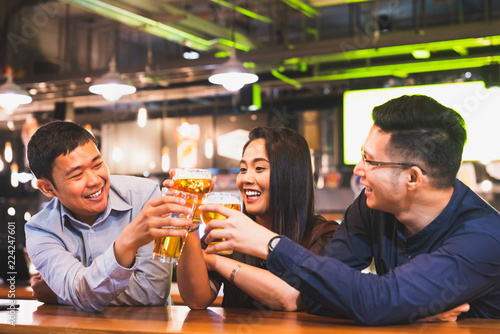 Photography Group of happy Asian friends or office colleague coworkers celebrate toast beer pint together at pub restaurant or club
