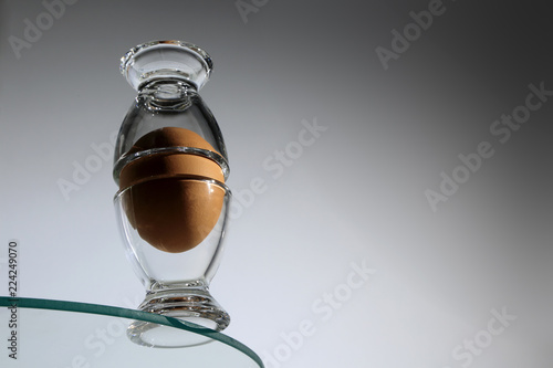 Jajko kurze w kieliszku na krawędzi szklanych mebli.