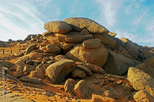 A large mound of boulders against a pale blue sky photo