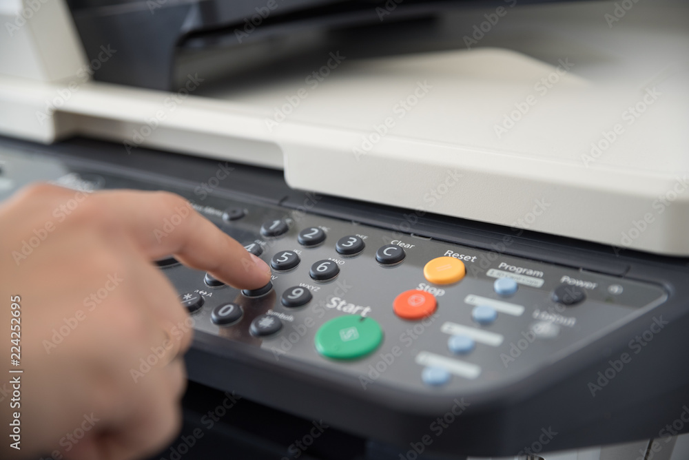 Office worker works with a multi-function device and sets the number of copies to print Office worker works with a multi-function device and sets the number of copies to print