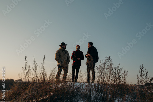 Four friends stand on a hill during a beautiful sunset. Winter trip. Relax and meeting friends. Friendship and longevity.