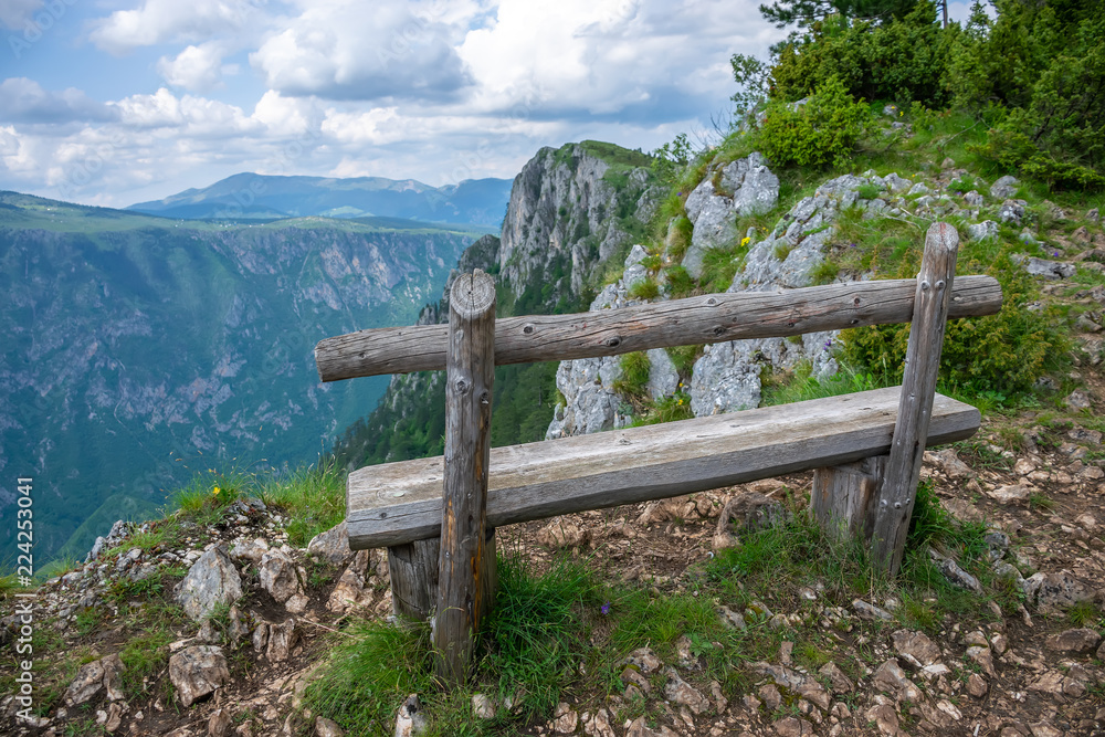 A picturesque wooden bench on top of a mountain canyon.