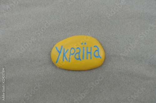 Україна, Ukraine country name carved and painted on a stone with beach sand background