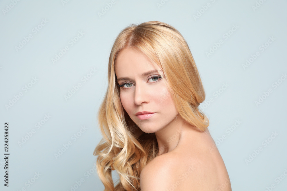 Naklejka premium Beautiful woman with healthy long blonde hair on light background