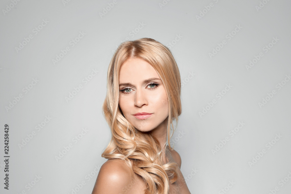Beautiful woman with healthy long blonde hair on light background