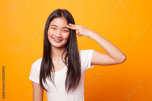 Beautiful young Asian woman holding fingers in gun gesture.