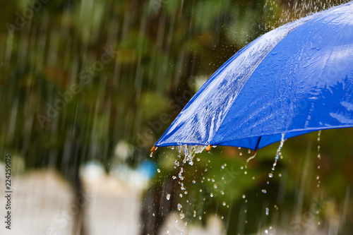 Bright umbrella under rain on street, closeup