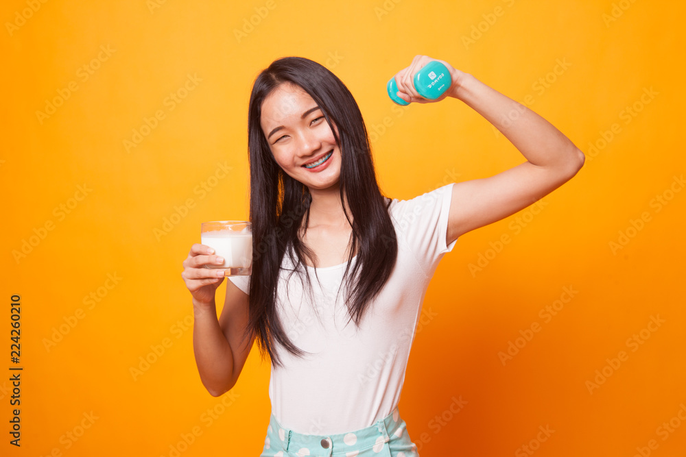 Healthy Asian woman drinking a glass of milk and dumbbell. Healthy Asian woman drinking a glass of milk and dumbbell.