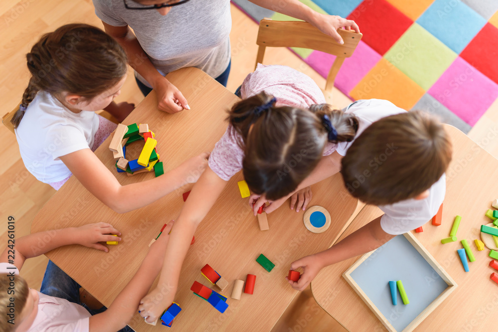 Preschool teacher with children playing with colorful wooden didactic ...