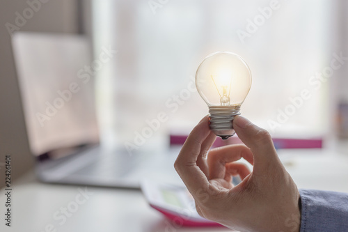 Concept Creativity and innovative or idea. Businesswoman hand holding light bulb with light bulbs of new idea and innovation.