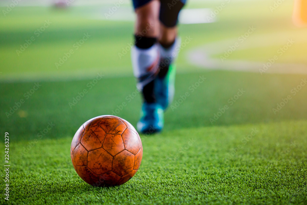 Soccer player put blue sport shoes shoot ball on artificial turf.