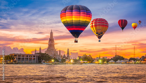 Colorful hot air balloons flying over Chao Phraya River near Wat Arun Temple at twilight in Bangkok  Thailand