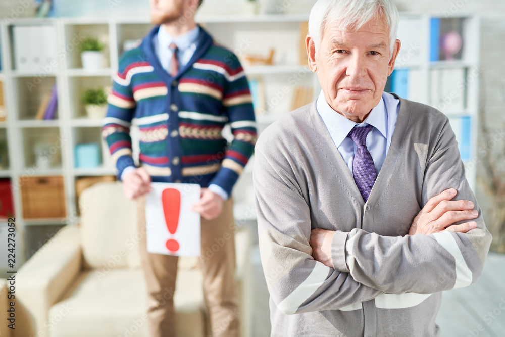 Obraz premium Waist up portrait of white haired senior man standing with arms crossed and looking at camera while posing in psychologists office, copy space