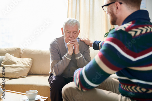 Fototapeta Back view portrait of male psychologist consoling depressed senior man during th