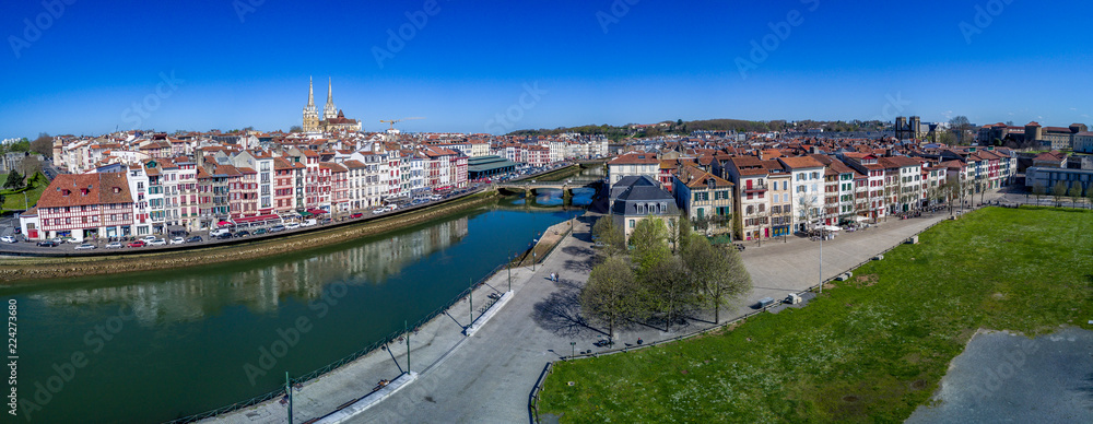 Panoramic aerial view of Bayonne with the Nive river reflecting colorful traditional French houses, medieval cathedral and blue sky