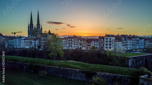 Sunrise with orange sky over the fortified medieval town of Bayonne, with traditional french houses, cathedral and a Roman tower 