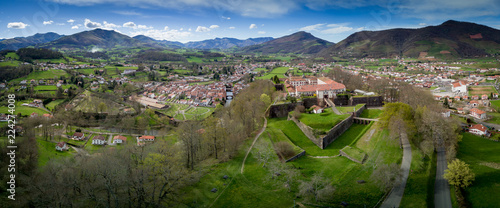 Fotografie Aerial panorama view of Saint Jean Pied de Port, a fortified military town in the Pyrenees along the el camino de santiago, with blue sky abd lush green pasture