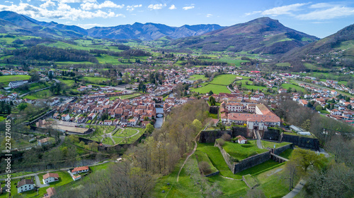 Aerial panorama view of Saint Jean Pied de Port, a fortified military town in the Pyrenees along the el camino de santiago, with blue sky abd lush green pasture. Star shaped Vauban fort.