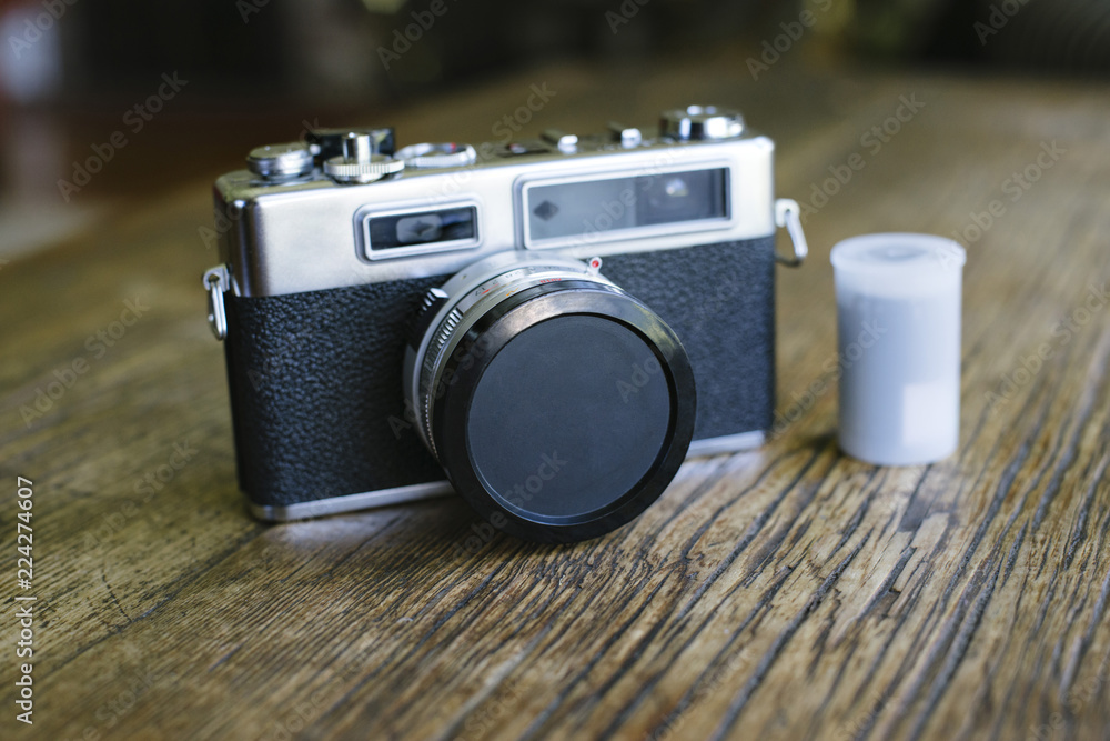 Front view of an old film camera with a lens cap and film canister