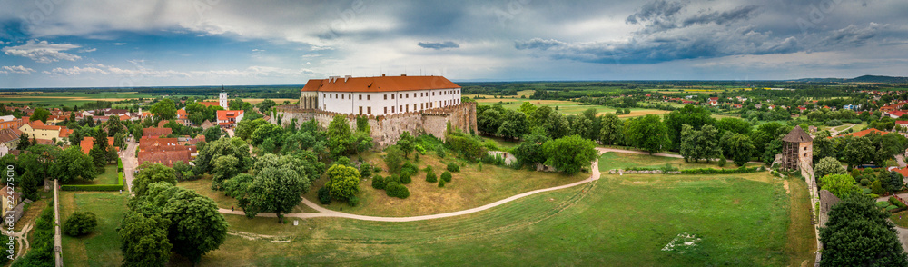 Aerial panorama of medieval Siklos castle in Hungary with brick walls, barbican, towers and Gothic chapel and stormy blue sky