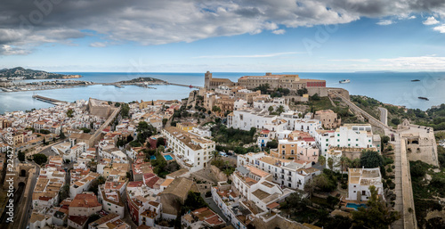 Aerial panorama of Ibiza town with fortifications, bastions, walls, churches, white houses against blue stormy cloudy sky photo