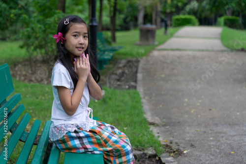 Asian child cute girl Sit on a green long chair in the garden