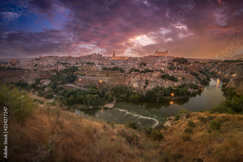Panoramic view of medieval Toledo in Spain with reflecting river purple, orange, blue sunset sky very peaceful