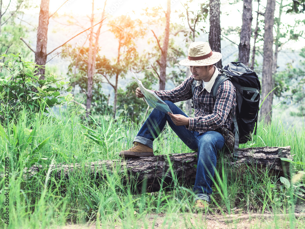 hiker male with backpack checks map to find directions in wilderness area hiker male with backpack checks map to find directions in wilderness area