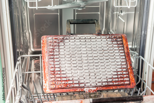 Dirty waffle iron lies on the dishwasher shelf