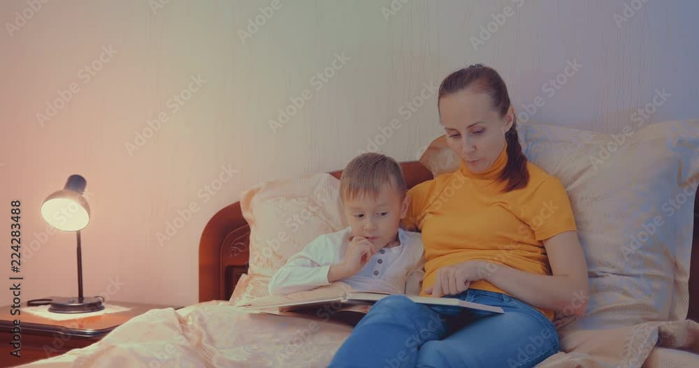 Mother and son reading a book on the couch before bedtime Mother and son reading a book on the couch before bedtime