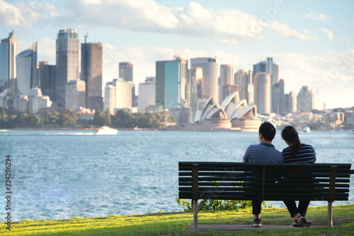 Asian couple sit and relax after running in a park in sydney