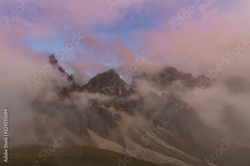 Dramatic sunset with rain clouds and rocky peaks in the Dolomite Alps, Italy, in summer