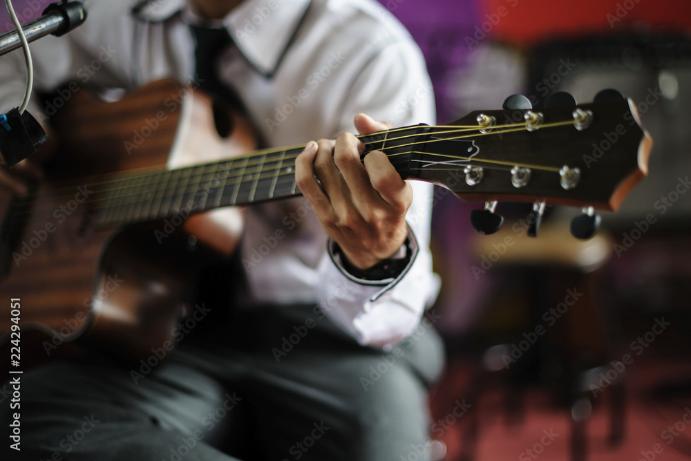 Fototapeta premium Young musician holding a guitar chord on stage.