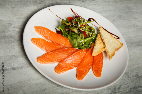 salmon slices served with rucola and tomato salad and toasted bread