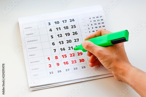Fotografie Hand crosses off the green marker days in the calendar