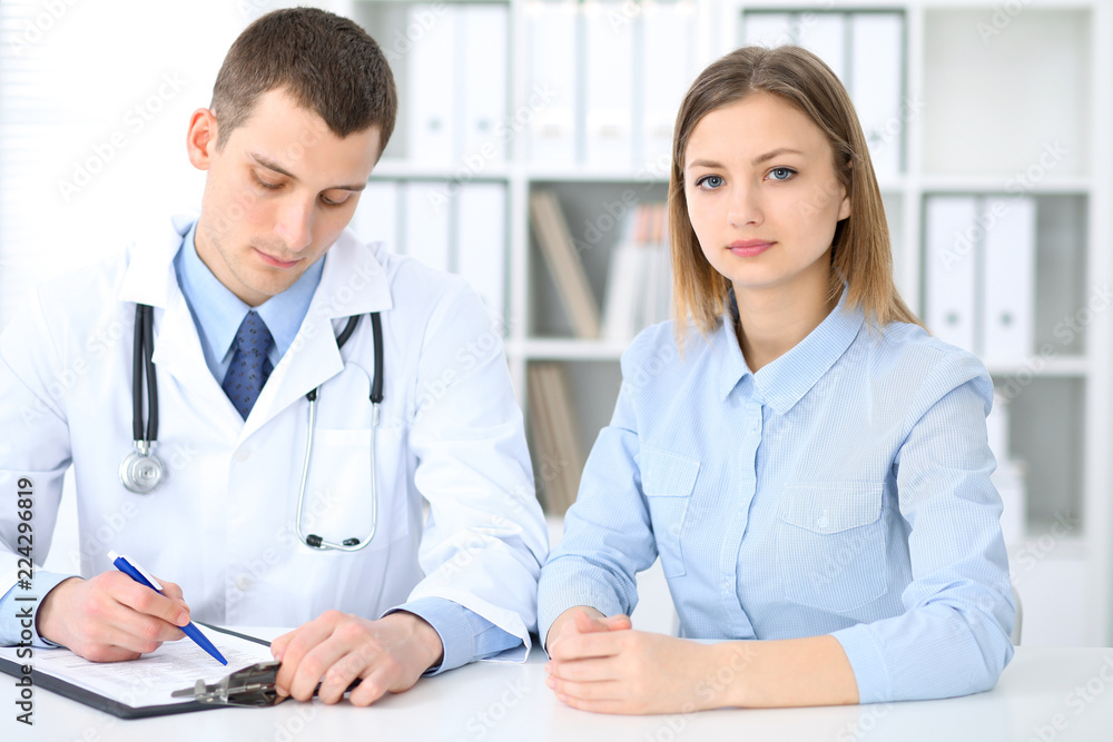 Doctor and patient sitting at the desk. Medicine and health care concept Doctor and patient sitting at the desk. Medicine and health care concept