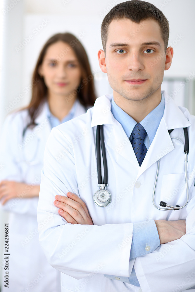 Friendly male doctor on the background of a female physician in hospital office Friendly male doctor on the background of a female physician in hospital office
