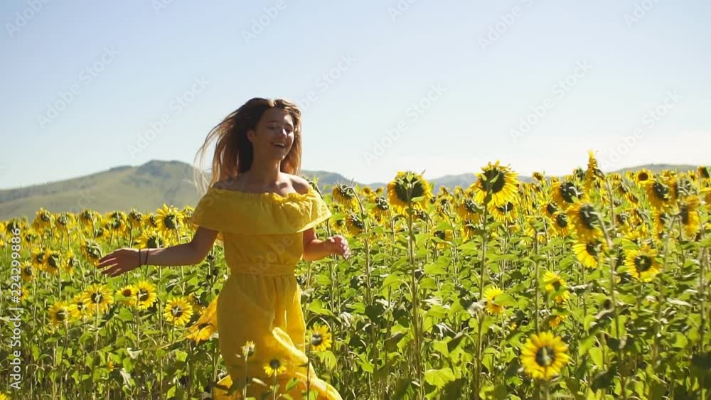 A young girl in a yellow dress runs in sunflowers. Slow motion. HD A young girl in a yellow dress runs in sunflowers. Slow motion. HD
