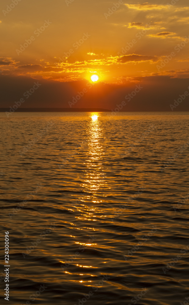 Golden Sunset into the sea with the silhouette of an island.