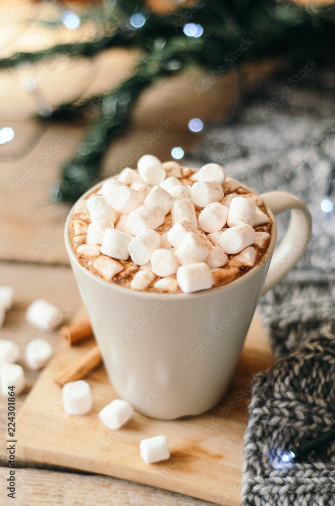 Hot cocoa with marshmallow and spices on wooden table with a gray knitted plaid. Cozy breakfast, New Year's Eve Hot cocoa with marshmallow and spices on wooden table with a gray knitted plaid. Cozy breakfast, New Year's Eve