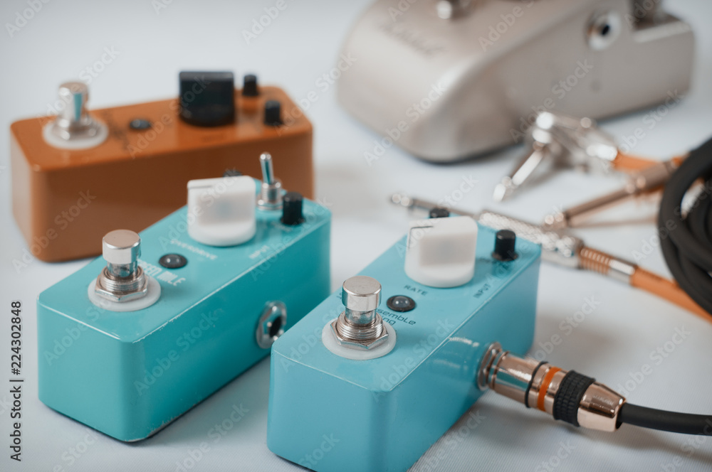 Electric guitar stomp effectors and cables in studio. Focus is on forehand switch box. Electric guitar stomp effectors and cables in studio. Focus is on forehand switch box.