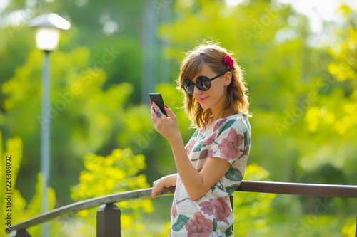 Cheerful girl using cellphone on a nice summer day.
