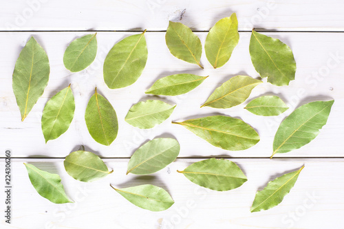 Lot of whole dry olive green bay laurel leaves flatlay on white wood photo