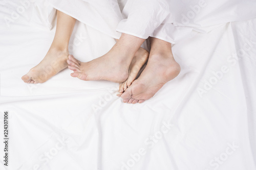 Close up of four feet in a bed. Couple sleeping