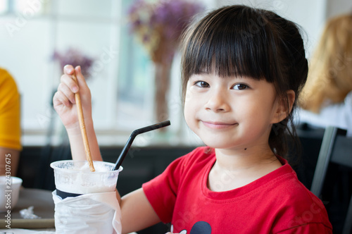 Close Up image of cute little girl drink milkshake in restaurant.