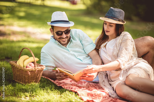 Beautiful couple enjoying picnic time outdoor reading book